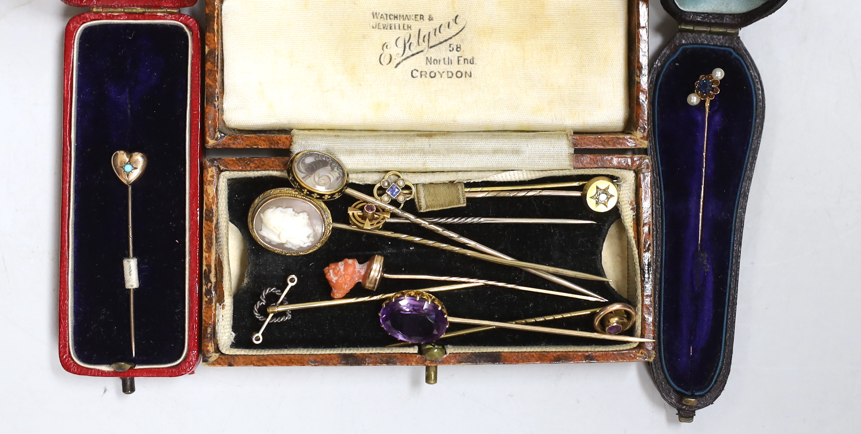 A Victorian yellow metal and black enamel stick pin, with hair beneath a glazed panel, 77mm and nine other assorted yellow metal and gem set stick pins including two 9ct, one 585 and one 15ct.